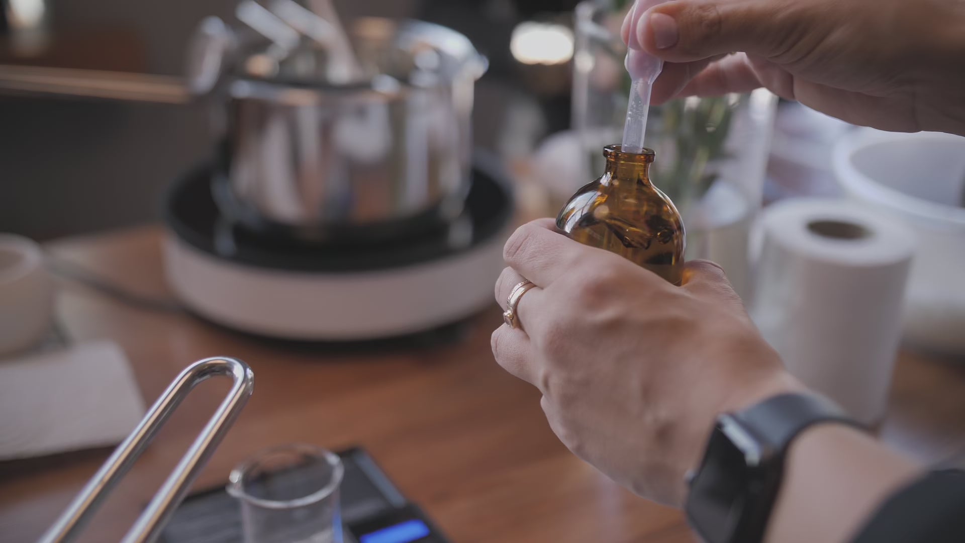 Load video: A pipette taking fragrance oil from a bottle and dropping it into a beaker mixture